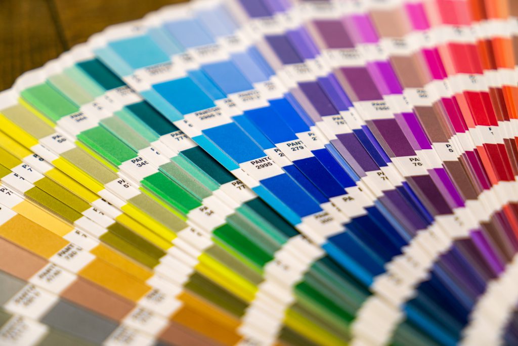A imagem mostra um leque de paletas de cores diversas, todas da marca Pantone.