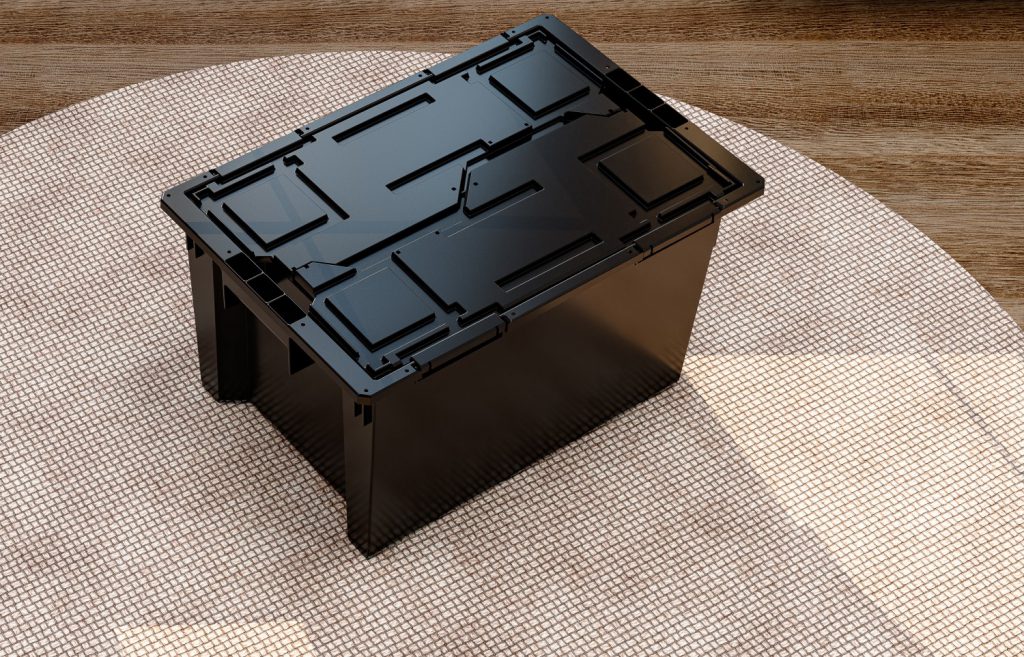 A imagem mostra uma caixa plástica preta no chão. Ela é vista de cima e está com a tampa fechada. 