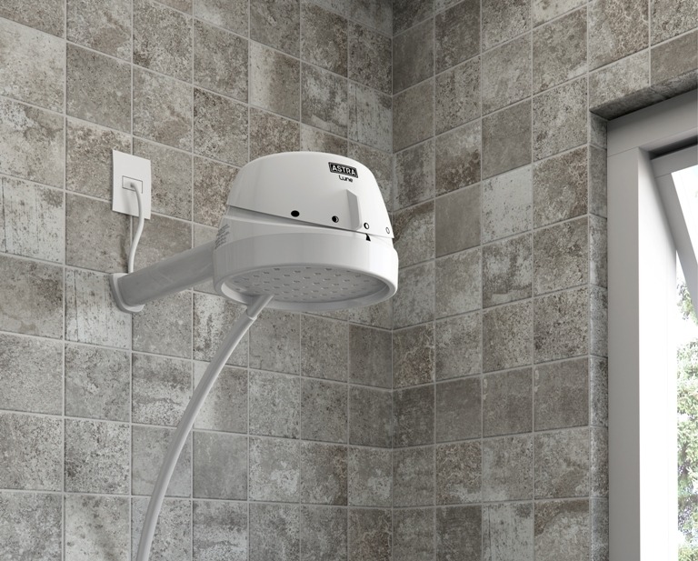  Um chuveiro branco da Astra está instalado em um banheiro com revestimento quadriculado cinza. 