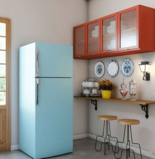Uma geladeira azul, uma bancada de madeira, dois banquinhos de madeira e um armário vermelho aparecem na imagem. 
