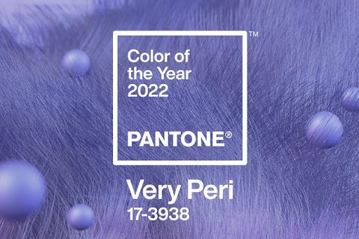 Imagem de divulgação oficial da Pantone sobre a cor do ano Pantone 2022. Ao fundo, texturas de pelos e bolinhas na tonalidade Very Peri e à frente uma caixa branca com o escrito “Color of the Year 2022 Pantone® Very Peri 17-3938.