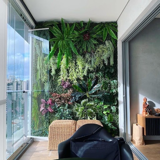 Jardim vertical com várias espécies de plantas em uma varanda com alguns assentos e proteção de vidro.