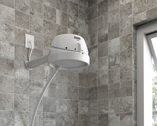 Uma ducha da Astra branca aparece em um banheiro com azulejos quadriculados cinzas. Ela representa como instalar chuveiro. 