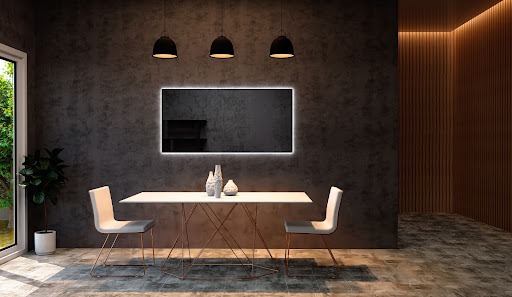 Sala de jantar, com uma mesa branca e duas cadeiras da mesma cor. Acima, três luminárias pendentes na cor preta, que representam o tipo de iluminação direta. Ao fundo, uma parede preta com um espelho retangular com moldura de LED da Astra.