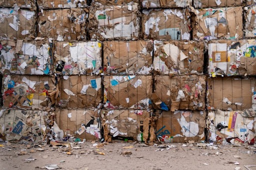 Vários lotes de lixo empilhados, especificamente de papel e papelão.
