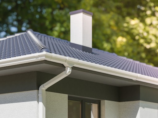 Na imagem temos uma casa mostrando a parte externa, principalmente o telhado, que conta com um sistema de calha de PVC instalado por todo o beiral do telhado. 