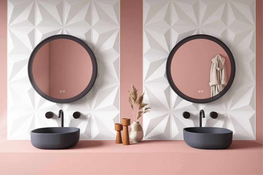 Na imagem vemos uma pia dupla na cor rosa, dois espelhos Nice instalados em uma parede com revestimento 3D. Ambas as cubas são da linha concreto da Astra Conceito. Ao meio temos alguns itens de decoração que compõem a bancada.