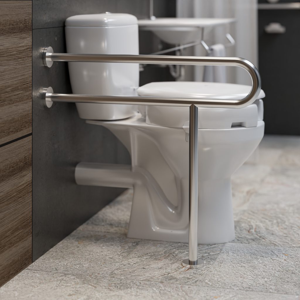 A imagem acima apresenta uma barra de acessibilidade de metal fixada na parede de um banheiro, ao lado de um vaso sanitário com caixa acoplada na cor branca. Ao fundo está um banheiro desfocado, mostrando um pouco de um gabinete também na cor branca.