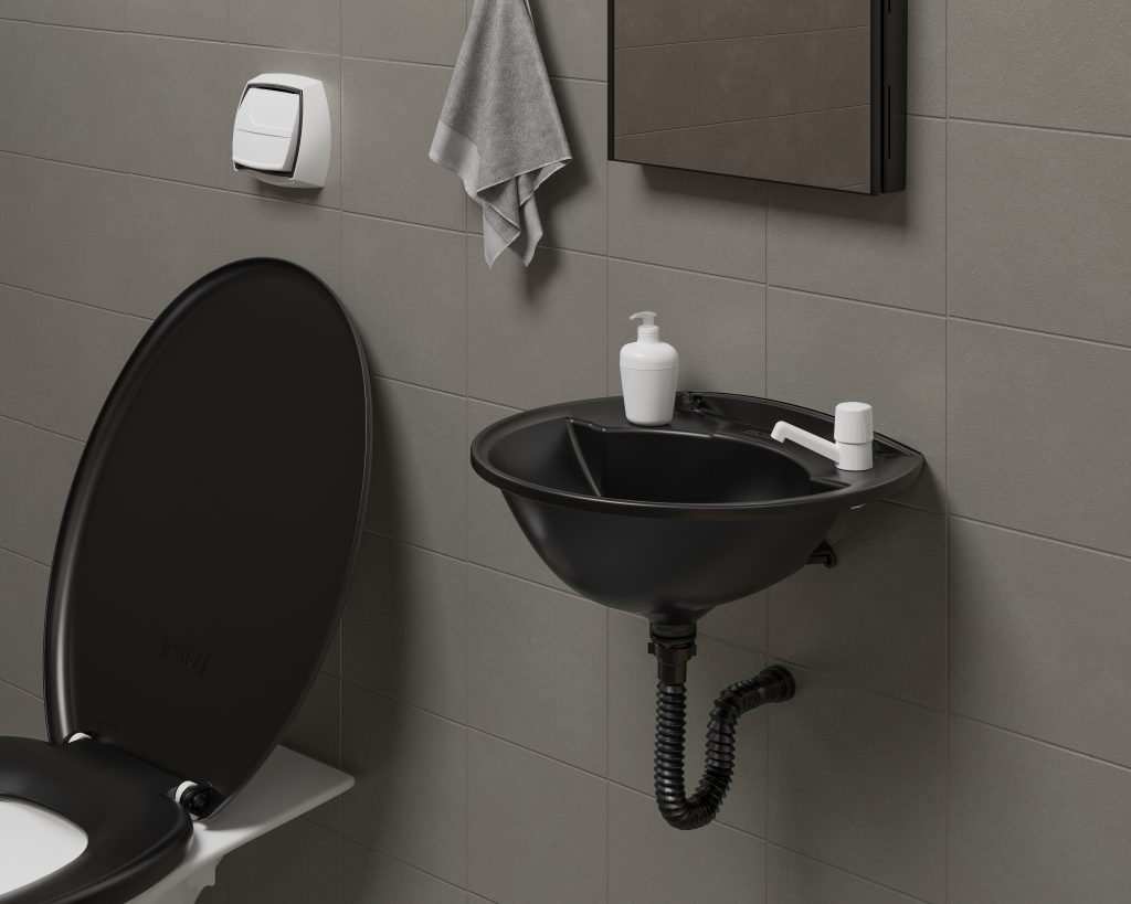 No banheiro temos uma pia plastica com um sifão embutido na parede na cor preta ao lado de vaso com um assento sanitário na cor preta com uma toalha de rosto em cima.