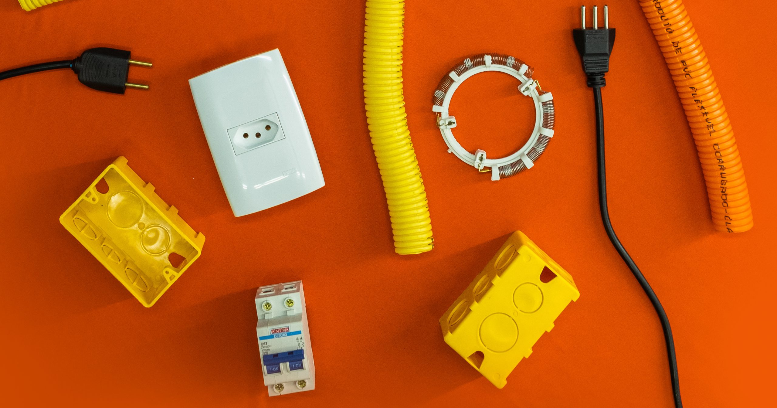 A imagem apresenta diversos produtos de elétrica ambientados em um fundo laranja. 